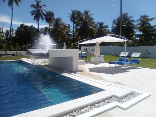 a swimming pool with a fountain in a yard at Oasi Encantada - Beach Resort in Santa Cruz de Barahona