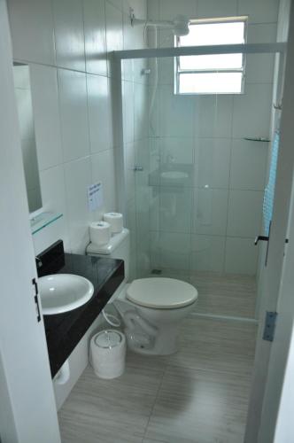 a white bathroom with a toilet and a sink at Pousada Guanumbi in Morretes