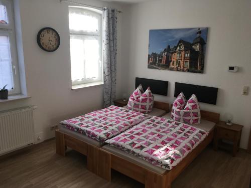 a bedroom with a bed with pink sheets and a clock at Ferienwohnung für Alt und Jung in Sonneberg