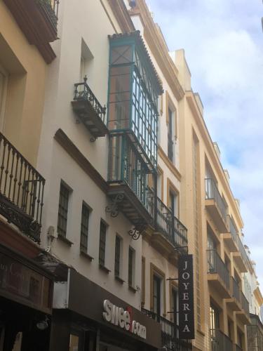 un edificio con balcones en un lateral en Calle Herbolarios, en Sevilla