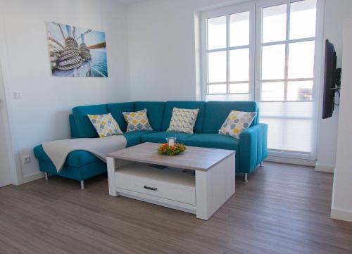 a living room with a blue couch and a coffee table at Fewo Strandleben Haus Strandperle in Börgerende-Rethwisch