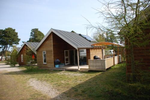 a small house with a porch and a deck at Hytteby – Hanstholm Camping – Thy Feriepark in Hanstholm