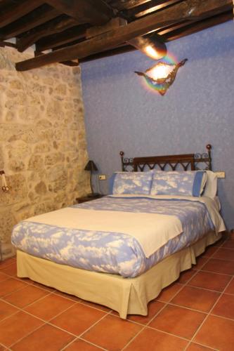 a bed in a bedroom with a blue wall at Posada Puerta Grande in Candelario