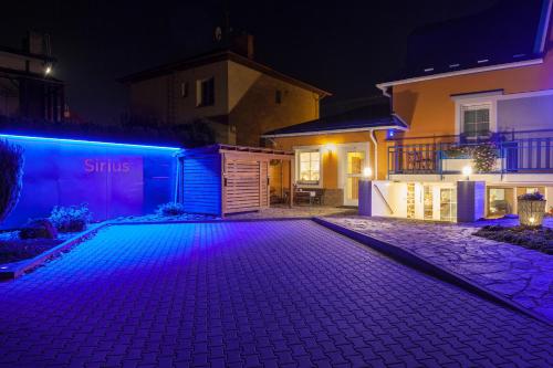 ヴィシュコフにあるPenzion Siriusの夜の私道の紫色の灯りを持つ家