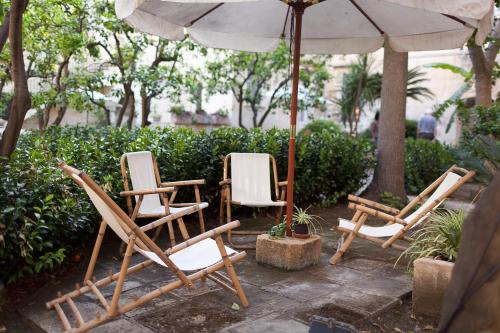 un gruppo di sedie e un ombrellone su un patio di Palazzo Pio Apartment a Lecce