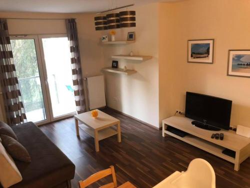a living room with a couch and a flat screen tv at Velence Wellness Apartman in Velence