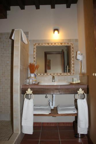 a bathroom with a sink and a mirror and towels at Posada Puerta Grande in Candelario