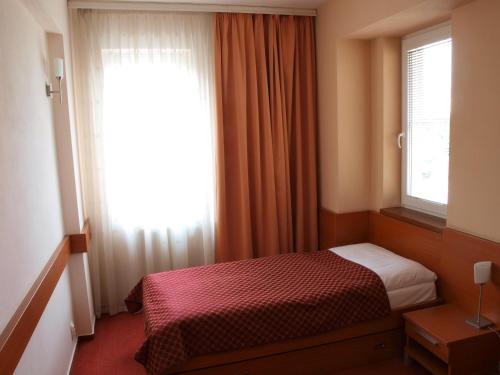 a small bedroom with a bed and a window at Hotel Dominika in Bratislava