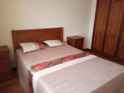 Apartamento Arosa في سانتا ماريا دا فييرا: غرفة نوم بسريرين ودواليب خشبية