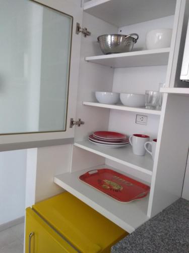 a kitchen with white shelves and a red plate at Barrancas del Monumento con Parking privado opcional in Rosario