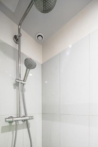 La salle de bains est pourvue d'une pomme de douche et de carrelage blanc. dans l'établissement Emmanuel & Béatrice, à Paris