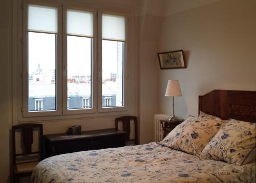een slaapkamer met een bed en een groot raam bij Emmanuel & Béatrice in Parijs