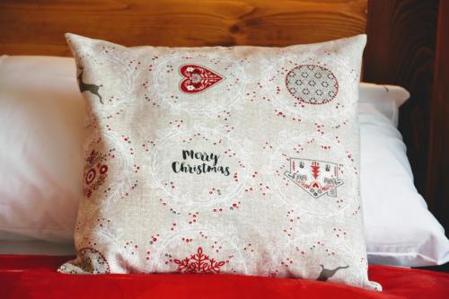 a pillow with merry christmas written on it on a bed at 4Roses Apartments in Smokovce
