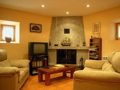 a living room with two couches and a tv at Casa rural Ornat Etxea in Vidángoz