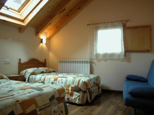 um quarto com 2 camas, uma janela e uma cadeira em Casa rural Ornat Etxea em Vidángoz