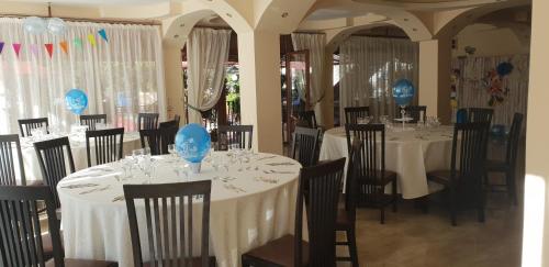 jadalnia z białymi stołami i krzesłami z niebieskimi dekoracjami w obiekcie Pensiunea Rozmarin w mieście Borca
