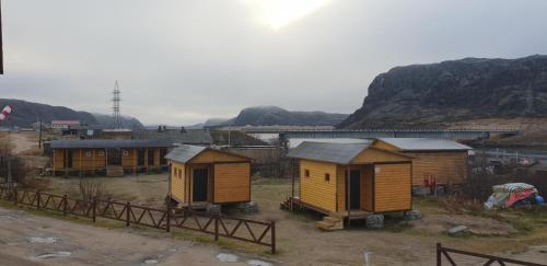 a group of tiny houses in a field with a train at Teriberka Tour in Teriberka