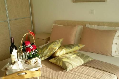 a bed with a bottle of wine and a basket of flowers at Apartments Maljevic Maca in Bar