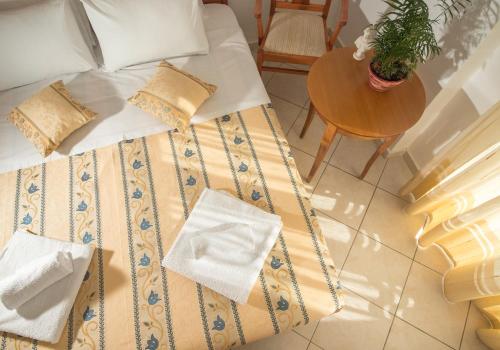 a bed with pillows and a table with a plant on it at Hotel Meltemi in Adamas
