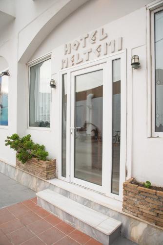 a white building with a sign on the side of it at Hotel Meltemi in Adamas