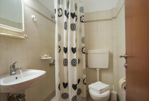 a bathroom with a toilet and a sink and a shower curtain at Hotel Meltemi in Adamantas