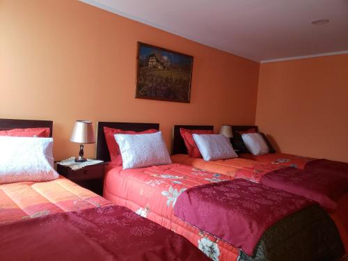 2 Betten in einem Zimmer mit orangefarbenen Wänden in der Unterkunft Hostal Nataly in Puerto Natales