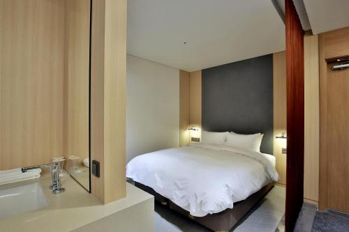 a bedroom with a white bed and a mirror at Hotel East9 in Gangneung