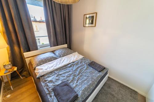 uma pequena cama num quarto com uma janela em Apartament przy Wyspie Młyńskiej em Bydgoszcz