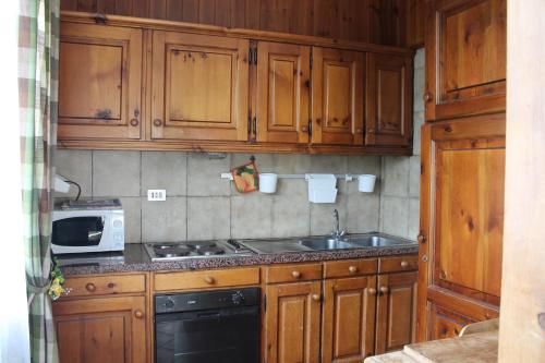 a kitchen with wooden cabinets and a stove and a sink at Jolly Residence in Bormio