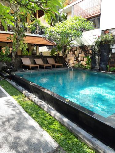 a swimming pool in front of a building at Merthayasa Bungalows in Ubud