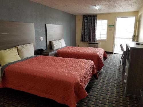 a hotel room with two beds and a television at Ameristay Inn & Suites in Orange