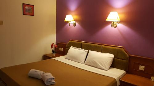 a hotel room with a bed with two towels on it at New Orchid Hotel Tuaran in Tuaran