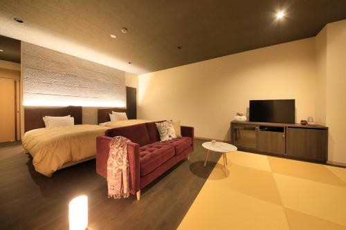 a bedroom with a bed and a couch and a tv at Atami Fuga in Atami