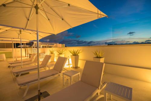 a patio with chairs and an umbrella on a roof at Oceanstone by RESAVA in Bang Tao Beach