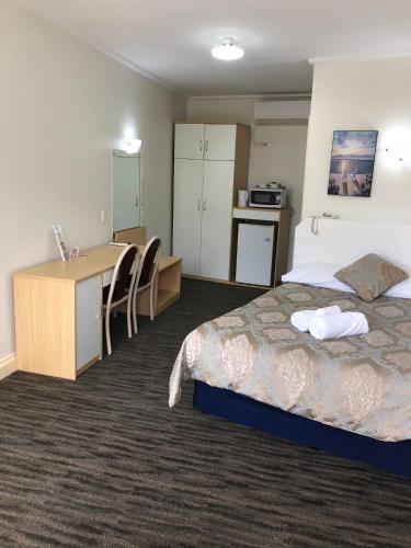 a hotel room with a bed and a desk and a kitchen at Jacksons Motor Inn in Adelaide
