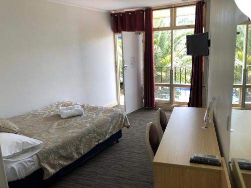 a hotel room with a bed and a desk and window at Jacksons Motor Inn in Adelaide