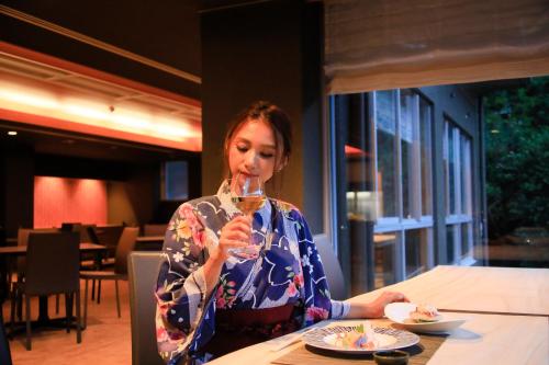 a woman sitting at a table holding a wine glass at Atami Fuga in Atami