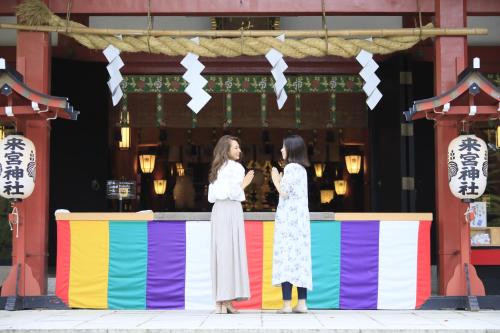 two women standing in front of a colorful fence at Atami Fuga in Atami