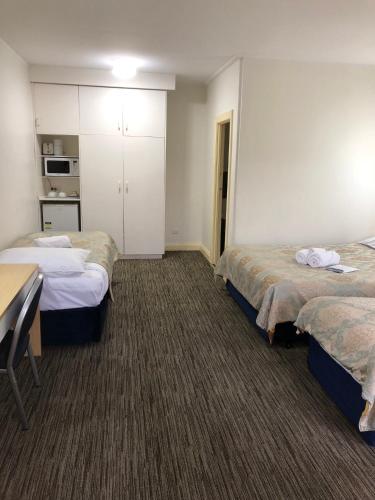 a hotel room with three beds and a table at Jacksons Motor Inn in Adelaide
