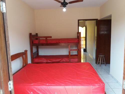 a bedroom with two bunk beds with red sheets at Chalés Bandeiras in Ubatuba