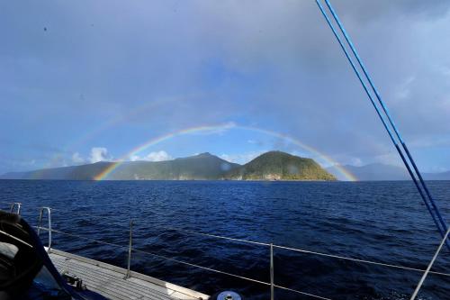 a rainbow over an island in the ocean with a boat at THE BAHI VILLA - Adults Only B&B in Les Trois-Îlets