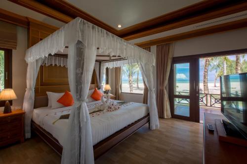 Schlafzimmer mit einem Himmelbett und Meerblick in der Unterkunft The Sunset Beach Resort - Koh Kho Khao in Ko Kho Khao