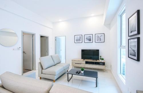 a white living room with a couch and a tv at KEEN Suites@Sutera Avenue in Kota Kinabalu