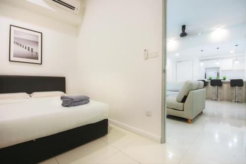 a white bedroom with a bed and a chair at KEEN Suites@Sutera Avenue in Kota Kinabalu