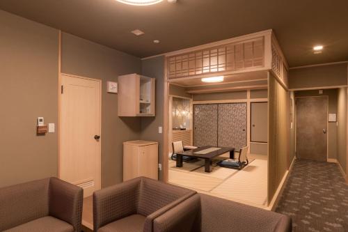 a living room with two chairs and a couch and a table at Atami Onsen Sakuraya Ryokan in Atami