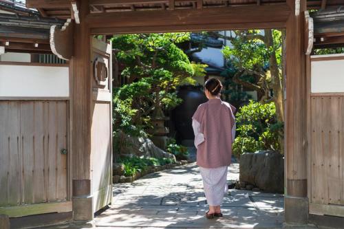 a woman walking through an entrance to a garden at Atami Onsen Sakuraya Ryokan in Atami