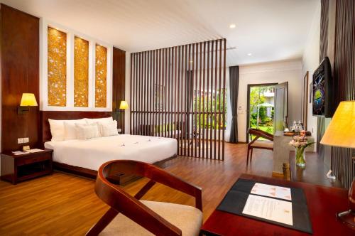 a bedroom with a bed and a desk and a chair at Sabara Angkor Resort & Spa in Siem Reap