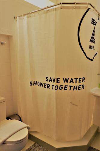 a bathroom with a shower curtain that says save water shower together at Z Hostel in Manila