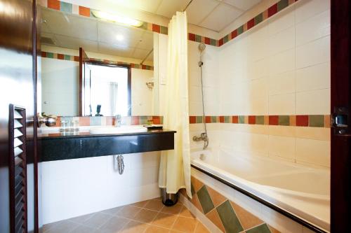 a bathroom with a tub and a sink and a mirror at ALUNA Ben Thanh Hotel in Ho Chi Minh City