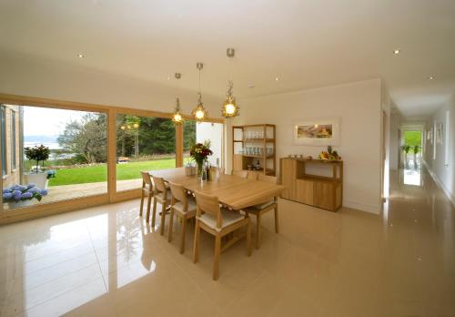 a kitchen and dining room with a wooden table and chairs at Ardtorna in Benderloch